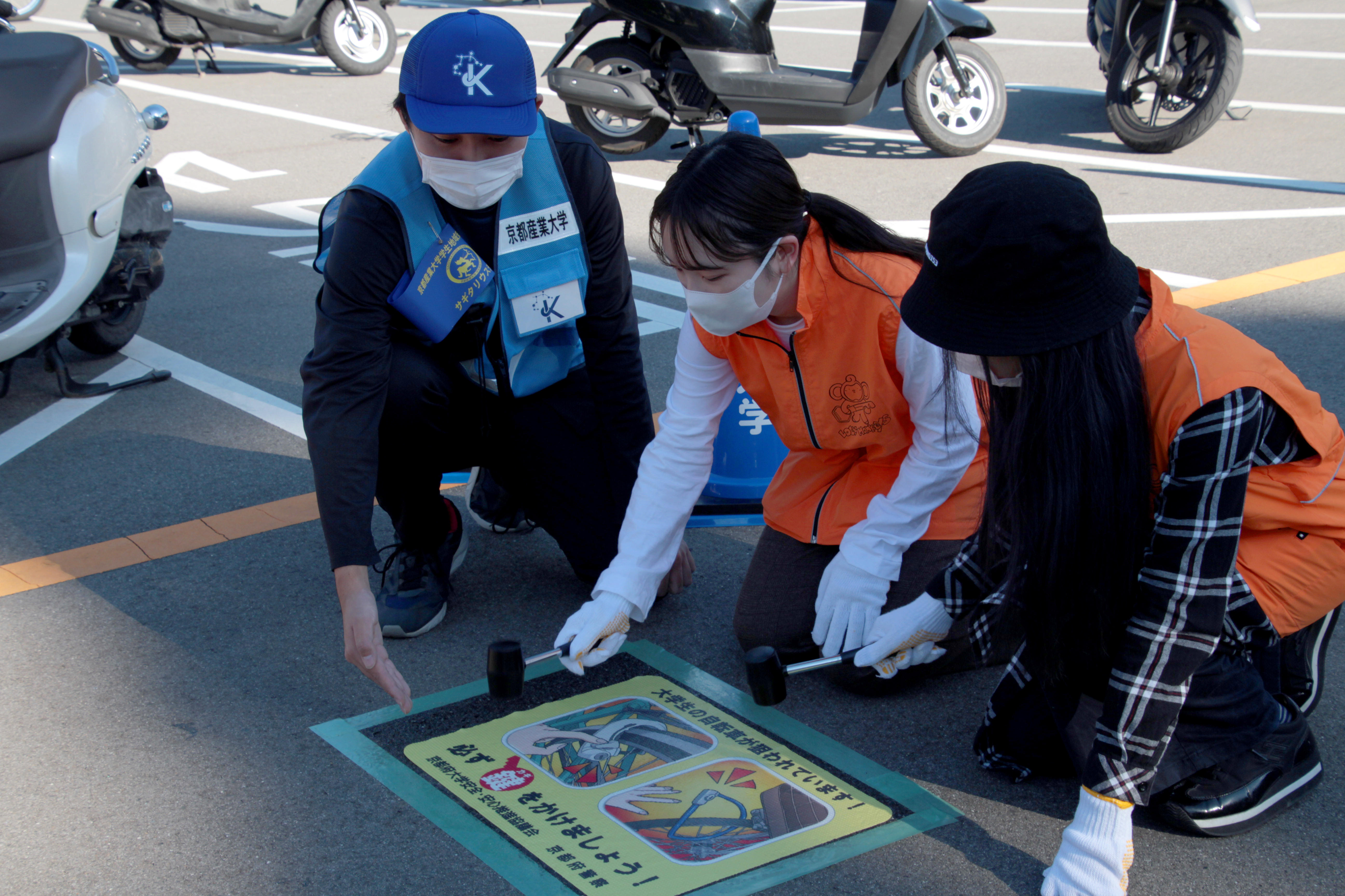 【京都産業大学】京都府内の大学初の試み！京都府警察本部と連携し自転車駐輪時の施錠徹底を啓発する路面シートを設置