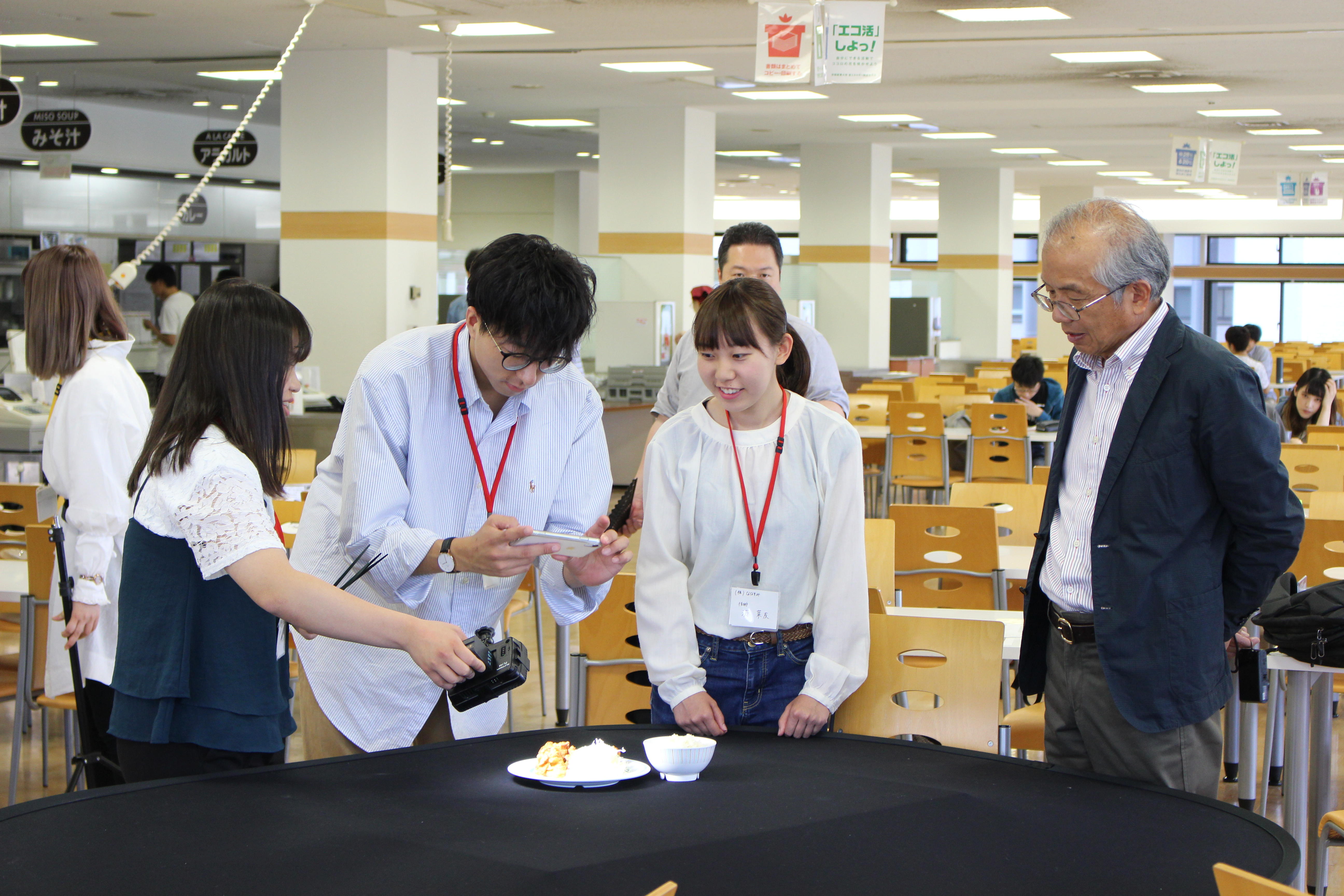 京都産業大学経営学部の学生が「CM制作に学ぶメディア戦略」をテーマに卒業生と協働して学生食堂のCMを制作！