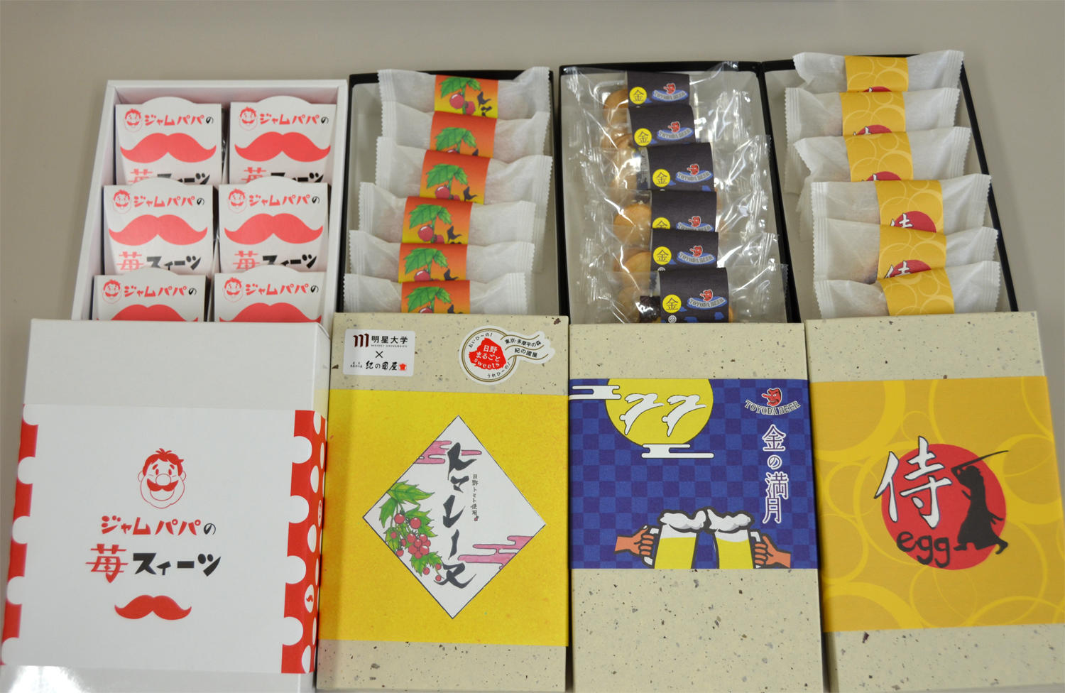 日野市の老舗「（株）紀の國屋」とのコラボレーションによる初の商品開発。経営学部の1年生が、地元食材を使用したお菓子4商品を商品化。 — 10月26日から販売開始 —