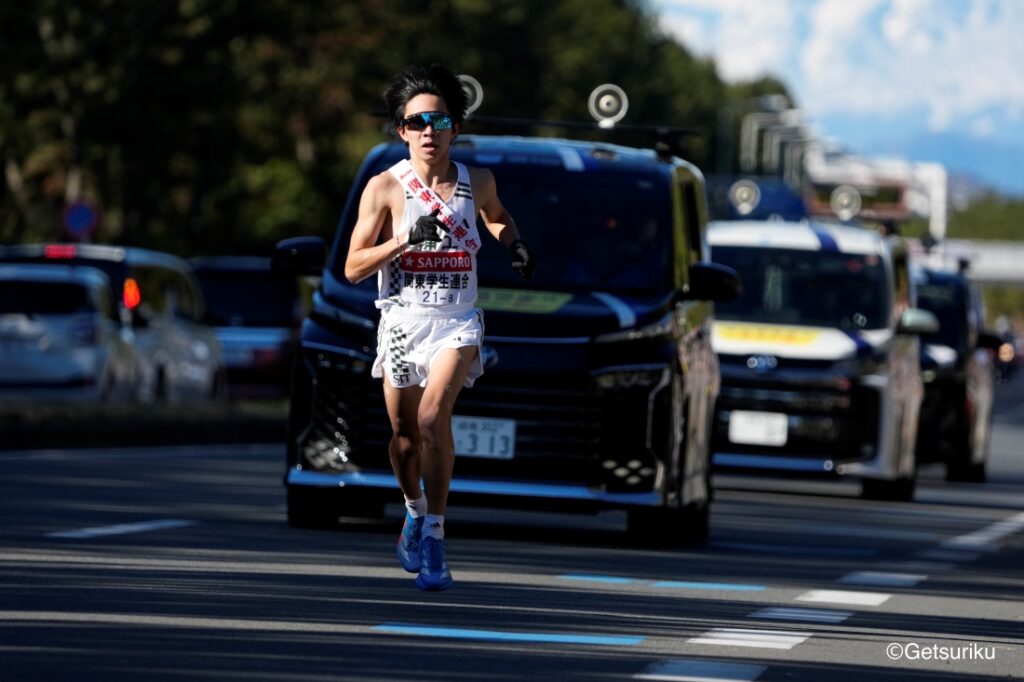 道路を走るランナーの前後を伴走車が並ぶ中、街路樹のある道を進む駅伝の様子